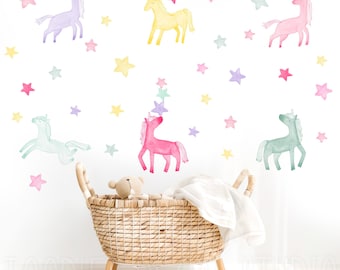 May include: A set of wall decals featuring five watercolor unicorns in purple, yellow, pink, light blue, and dark pink, surrounded by scattered stars in various pastel colors. Below the decals sits a woven wicker basket containing a teddy bear.