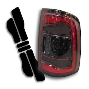 May include: A black and red automotive tail light assembly with the word "RAM" visible. Includes a set of black vinyl overlays. The tail light has a glossy black finish with red accents.