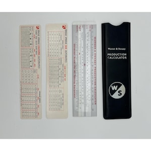 May include: A set of three rectangular off-white data cards and a silver-toned metal slide rule, accompanied by a black protective sleeve. The items feature printed technical text, tables, and the Warner & Swasey Production Calculator logo.