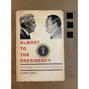 Könnte beinhalten: Ein Vintage-Buch mit dem Titel "Almost to the Presidency" von Albert Eisele. Das Cover zeigt Porträts von zwei Männern und das offizielle Siegel der Vereinigten Staaten. Das Buch ist eine Biografie von zwei amerikanischen Politikern.