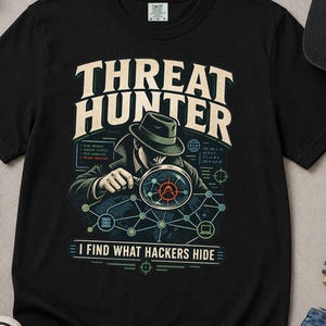 May include: A black short-sleeve t-shirt featuring a graphic of a detective looking through a magnifying glass at a digital network. The text reads THREAT HUNTER and I FIND WHAT HACKERS HIDE. The shirt is displayed with a black baseball cap, a notebook, a pen, and sneakers.