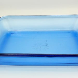 Könnte beinhalten: Eine rechteckige, hellblaue Glasbackform mit dunkelblauem Rand und Griffen. Die Form ist leer und steht auf einer weißen Oberfläche. Die Form ist etwa 33 cm lang und 23 cm breit.