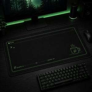 May include: Black rectangular desk mat with a green outline and a green graphic of a teacup. The mat has the text "breathe in... breathe out" and a keyboard. The desk mat is on a black desk.
