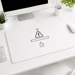 Può includere: Tappetino da scrivania rettangolare bianco con grafica in bianco e nero. La grafica include un simbolo di avvertimento pixelato, una barra orizzontale, il numero "404" e una tazza di caffè fumante. Il tappetino è su una scrivania bianca con un computer e accessori.