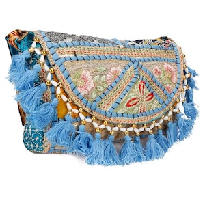Può includere: Borsa a tracolla ricamata con chiusura a patta. La borsa presenta un design patchwork con ricami floreali, nappe blu e dettagli di perline dorate. La borsa è in stile bohémien.