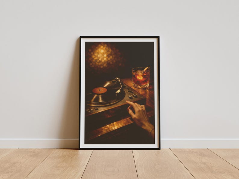 May include: Framed print of a record player with a vinyl record in place. A hand is positioned near the controls. A cocktail with an orange peel garnish is on the table. The image has a warm, inviting colour palette.