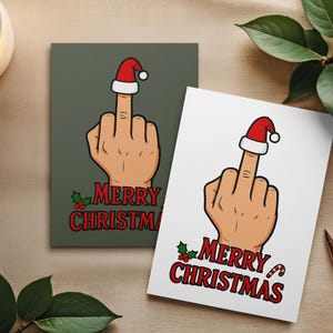 以下が含まれることがあります： サンタ帽をかぶった中指を立てた手のクリスマスカードが2枚。カードには赤い文字で「MERRY CHRISTMAS」と書かれています。1枚は緑色の背景、もう1枚は白い背景です。