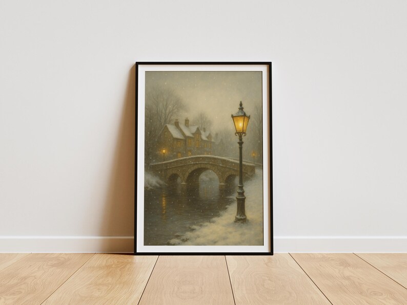 May include: Framed art print of a winter scene. A stone bridge arches over a river, with a building and trees in the background. A lit lamppost stands in the foreground, and snow falls gently. The artwork is in a black frame.