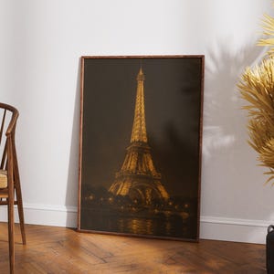 May include: A framed print of the Eiffel Tower at night, illuminated with golden lights. The artwork is set against a dark background, with the tower's reflection visible in the water below. The frame is a warm brown color.