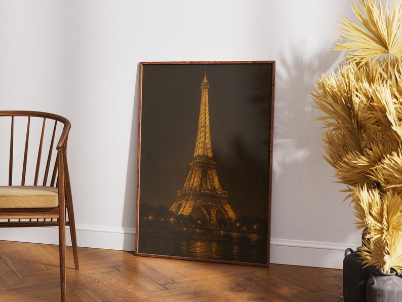 May include: A framed print of the Eiffel Tower at night, illuminated with golden lights. The artwork is set against a dark background, with the tower's reflection visible in the water below. The frame is a warm brown color.