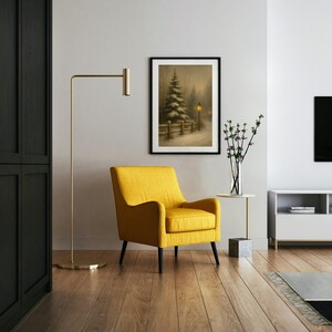 May include: A cozy living room scene featuring a framed winter landscape painting, a bright yellow armchair, and a gold floor lamp. The room has hardwood floors and a modern white cabinet. A vase of flowers sits on a small side table.