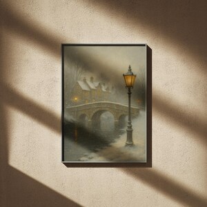 May include: Framed art print depicting a snowy winter scene. A stone bridge arches over a river, leading to snow-covered buildings. A lit lamppost stands in the foreground, casting a warm glow in the cold, misty atmosphere.