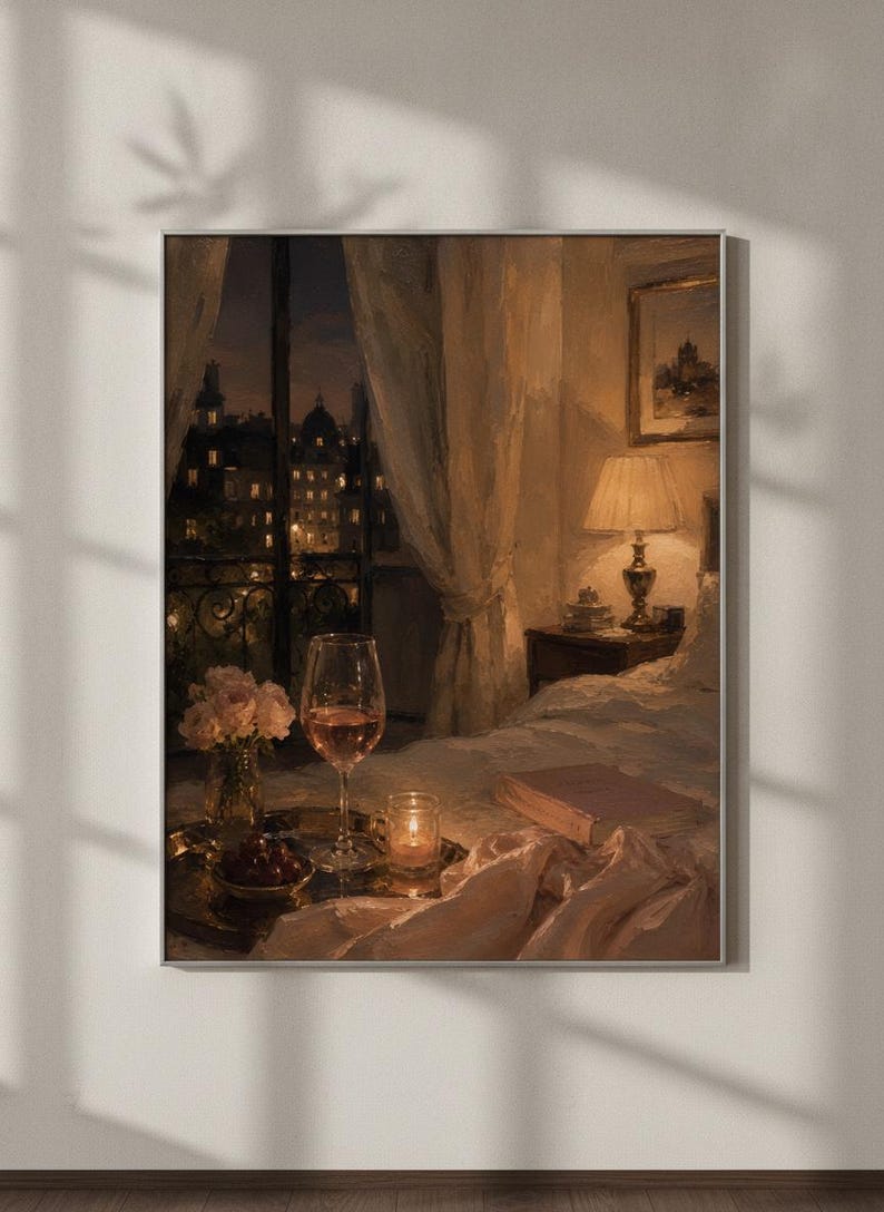 May include: A framed wall art print depicting a bedroom interior at night. A bedside lamp illuminates a bed with a book, a tray holding a glass of wine, a small bowl of cherries, and a vase of flowers. A window reveals a dark city skyline view.