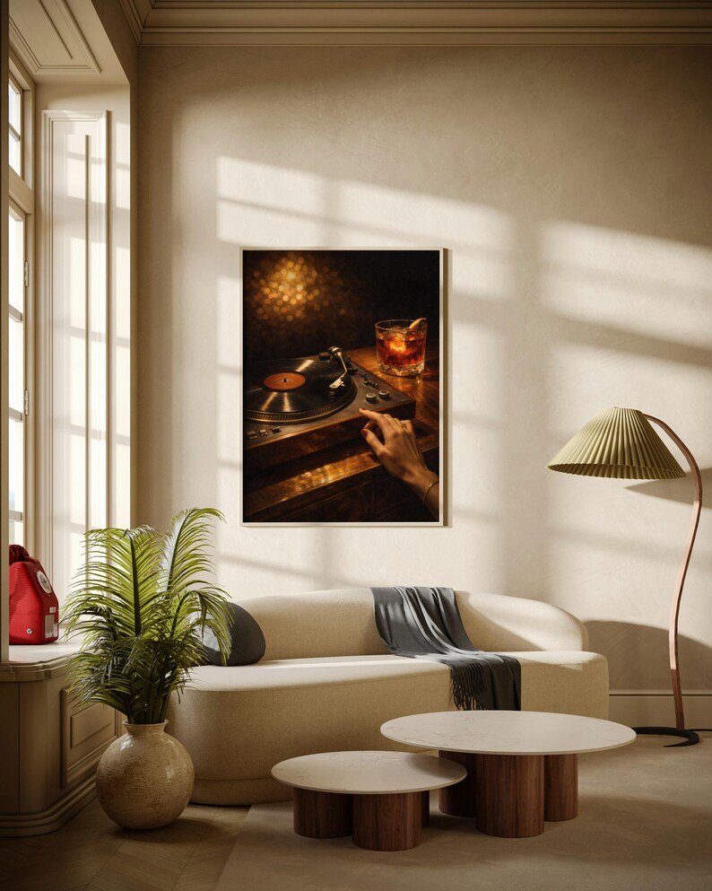 May include: A framed print showing a vintage record player with a vinyl record, a cocktail, and a hand. The room features a cream sofa, round coffee tables, and a green lamp. The scene is warm and inviting.