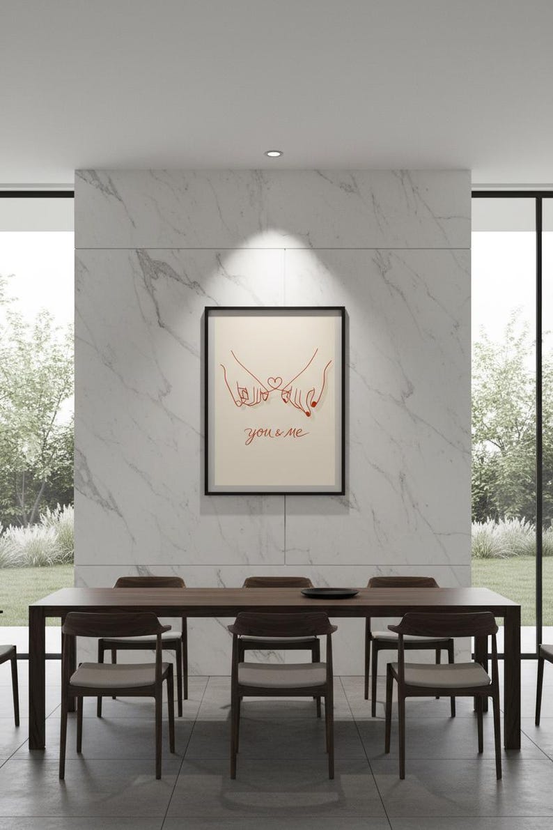 Puede incluir: Un cuadro enmarcado con un dibujo lineal de dos manos con los me&ntilde;iques entrelazados y un coraz&oacute;n. Las palabras "you & me" est&aacute;n escritas en rojo. El cuadro cuelga sobre una mesa de comedor de madera oscura con sillas a juego.