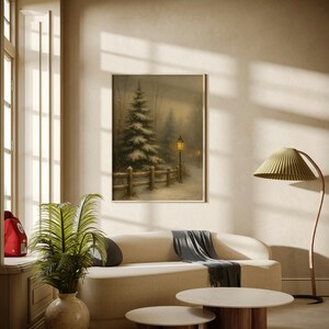 May include: A cozy living room scene featuring a framed winter landscape painting above a cream-colored sofa. Two round coffee tables with wooden bases and marble tops sit in front of the sofa. A green leafy plant in a beige vase adds a touch of nature.
