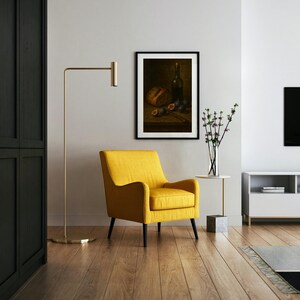 Pode incluir: Uma sala de estar moderna com uma poltrona amarela, um candeeiro de p&eacute; dourado e uma pintura emoldurada de natureza morta. A pintura mostra uma garrafa, p&atilde;o e figos. Uma mesa lateral branca com um vaso de flores. Ch&atilde;o de parquet.