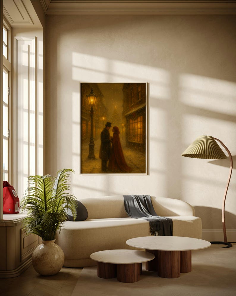 May include: A framed print showing a romantic winter scene with a couple embracing on a snowy street, lit by a gas lamp. The artwork is displayed above a cream sofa, with a round coffee table and a floor lamp.