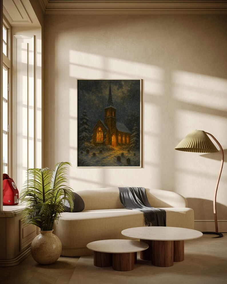 Peut inclure: Tableau encadr&eacute; d'une &eacute;glise la nuit, &eacute;clair&eacute;e par une lumi&egrave;re chaleureuse, avec de la neige qui tombe. L'&oelig;uvre est suspendue au-dessus d'un canap&eacute; cr&egrave;me avec un plaid gris. Deux tables basses rondes avec des bases en bois sont devant le canap&eacute;.