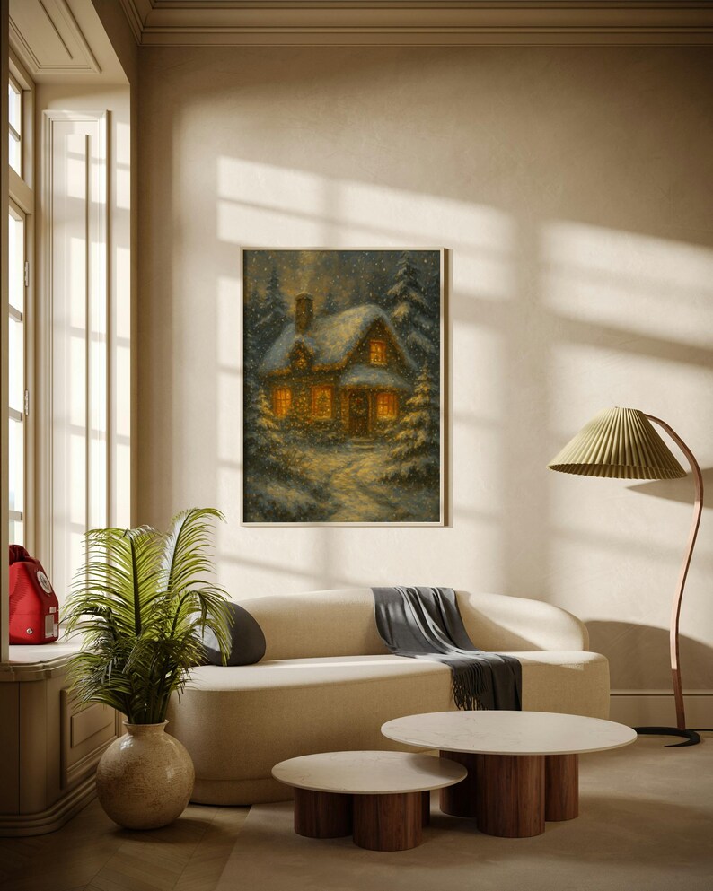 K&ouml;nnte beinhalten: Ein gerahmtes Winterlandschaftsbild zeigt ein gem&uuml;tliches Cottage mit beleuchteten Fenstern, umgeben von schneebedeckten B&auml;umen. Das Kunstwerk h&auml;ngt &uuml;ber einem cremefarbenen Sofa mit einem grauen &Uuml;berwurf.