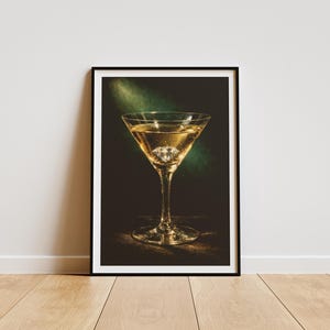 Puede incluir: Impresi&oacute;n enmarcada de un martini en una copa cl&aacute;sica. La bebida dorada contiene un gran cubito de hielo en forma de diamante. El fondo oscuro est&aacute; iluminado por un foco verde, creando un contraste llamativo. Marco negro.