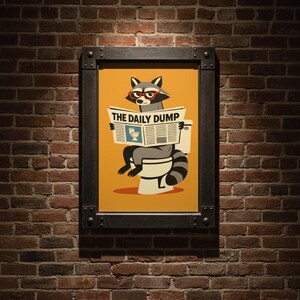 Op de afbeelding: Ingelijste kunstdruk met een cartoon wasbeer met een bril die een krant leest met de titel "THE DAILY DUMP" terwijl hij op een toilet zit. Het kunstwerk heeft een gele achtergrond en is geplaatst tegen een bakstenen muur.