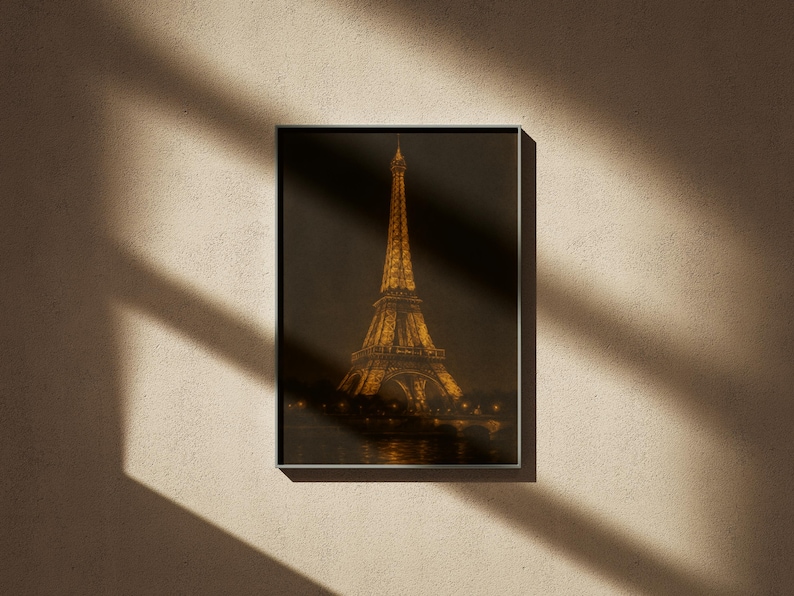 May include: Framed print of the Eiffel Tower at night, illuminated with golden lights. The artwork is set against a dark background, with the tower's silhouette and the Seine River visible. The print is in a silver frame, mounted on a textured beige wall.