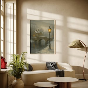 May include: A framed painting depicts a winter scene with a stone bridge, a lamppost, and snow-covered buildings. The artwork hangs above a cream-colored sofa with a dark gray throw. Two round coffee tables with wooden bases and marble tops sit in front of the sofa.