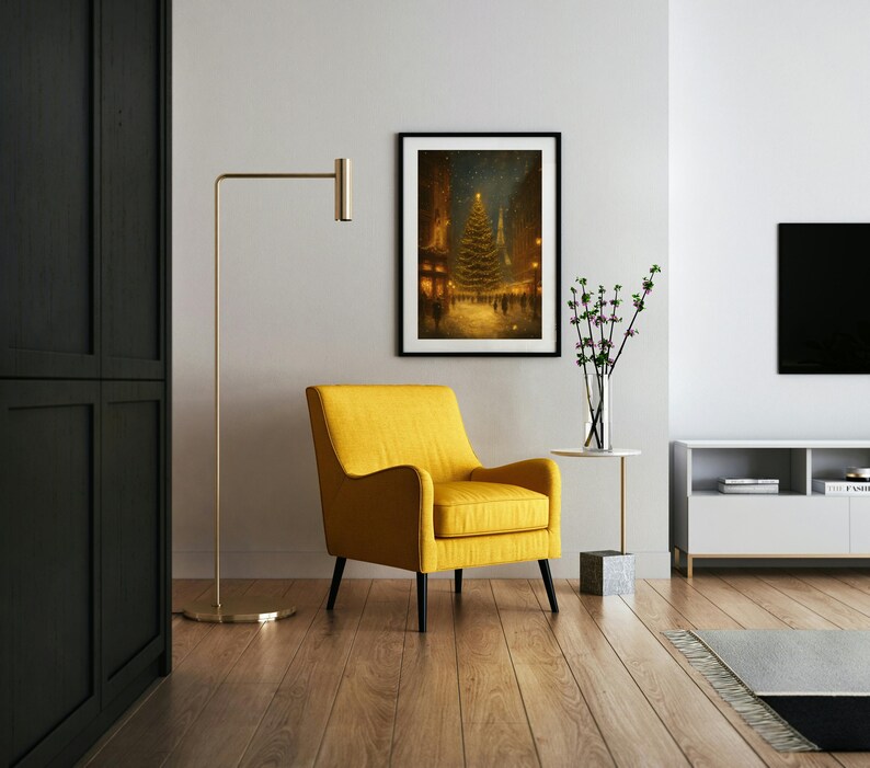 May include: A framed art print depicts a Christmas tree in a snowy town square, lit with golden lights. A yellow armchair with black legs sits below the artwork. A gold floor lamp and a white side table with a vase of flowers complete the scene.
