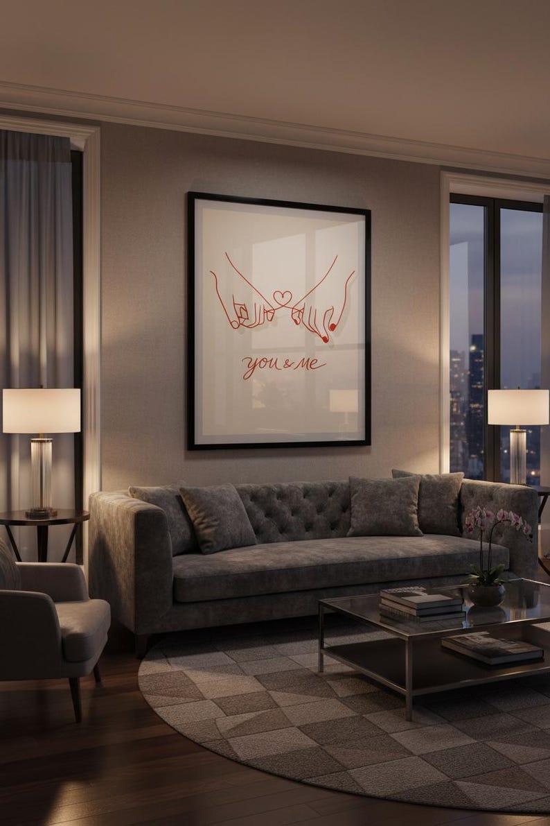 Puede incluir: Una impresi&oacute;n art&iacute;stica enmarcada con un dibujo lineal rojo de dos manos entrelazadas por los me&ntilde;iques, con un coraz&oacute;n y la frase "you & me". La obra de arte cuelga sobre un sof&aacute; gris en un sal&oacute;n moderno.