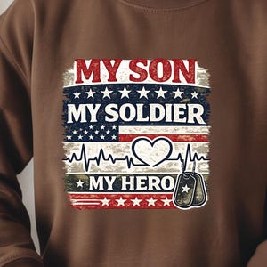 May include: Brown sweatshirt with a patriotic design. The design features the text "MY SON MY SOLDIER MY HERO" in red and white, with an American flag motif and dog tags. A heartbeat graphic is also included.