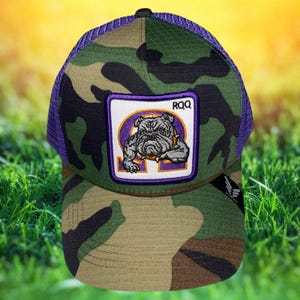May include: Camouflage baseball cap with a purple mesh back and a black top button. The front features a patch with a bulldog illustration, the letters RQQ, and the Greek letter Omega.