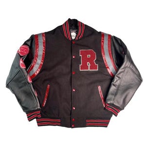 Puede incluir: Una chaqueta universitaria negra con un parche grande de la letra R roja en el pecho, mangas de cuero negro y puños y cuello acanalados con rayas rojas y negras. La chaqueta incluye botones de presión rojos y detalles de cuero rojo en los hombros.