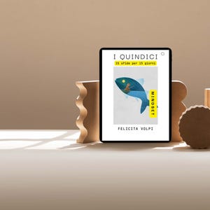 Puede incluir: Una tableta digital muestra un gráfico de un pez azul con una persona dentro. El texto en la tableta dice "I QUINDICI" y "15 sfide per 15 giorni". La tableta está apoyada por formas geométricas de madera.