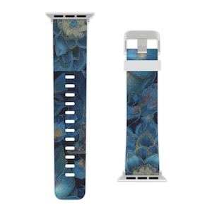 Puede incluir: Una correa de reloj con un diseño floral. La correa presenta un patrón de flores azules y doradas sobre un fondo oscuro. La correa está hecha de un material flexible y tiene un cierre y conectores de color plateado.