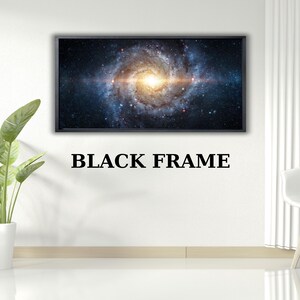 May include: A framed print featuring a vibrant depiction of a galaxy with swirling blues, oranges, and yellows. The artwork is set in a black frame, with the text "BLACK FRAME" below. The image is displayed in a modern, minimalist interior setting.
