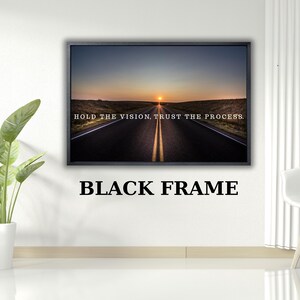 Op de afbeelding: Een ingelijste print met een weg die naar een zonsondergang leidt. De tekst luidt: "HOLD THE VISION, TRUST THE PROCESS." De lijst is zwart, met de tekst "BLACK FRAME" eronder.