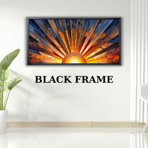 May include: A framed artwork depicting a stylized sunrise. The artwork features a sunburst design with a black frame. The sun's rays are composed of various shades of orange, yellow, and blue, creating a vibrant and warm aesthetic. The text "BLACK FRAME" is below the artwork.