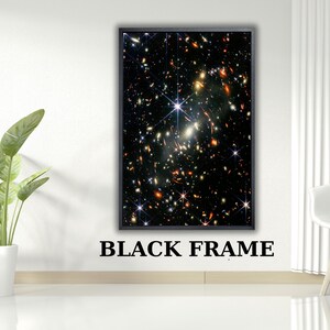 May include: A rectangular wall art piece featuring a deep space nebula image with numerous bright stars and distant galaxies in shades of orange, white, and blue, enclosed within a thin, solid black frame. The text BLACK FRAME is below.