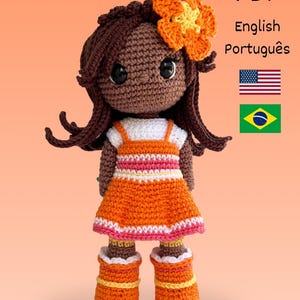Pode incluir: Boneca de crochê com cabelo castanho e uma flor laranja. A boneca usa um vestido laranja com detalhes brancos e rosa, e botas laranja. A imagem inclui o texto "PDF English Português".