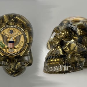 May include: A transparent skull sculpture filled with golden bullet casings. The front of the skull features a gold emblem with an eagle and the text "Office of Inspector General, Agency for International Development."