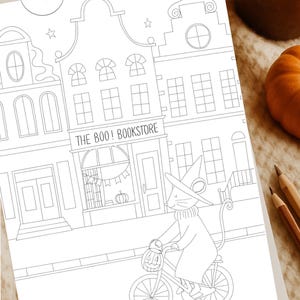 Peut inclure: Illustration en noir et blanc d'une scène d'Halloween. Une souris avec un chapeau de sorcière fait du vélo avec un panier en forme de citrouille devant un bâtiment avec l'inscription "THE BOO! BOOKSTORE". Des étoiles et une lune sont dans le ciel.