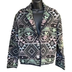 May include: Black blazer with a geometric pattern in shades of green, pink, and blue. The jacket has a notched collar, two buttons, and a tailored fit. The pattern features diamond and triangle shapes.
