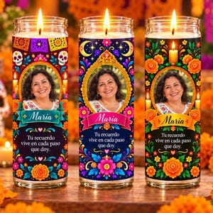 Pode incluir: Três velas cilíndricas de vidro com pavios acesos, cada uma com um retrato circular central de uma mulher chamada Maria, rodeado por padrões florais coloridos, caveiras de açúcar e o texto em espanhol: Tu recuerdo vive en cada paso que doy.