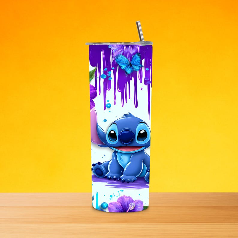 K&ouml;nnte beinhalten: Ein zylindrischer Edelstahlbecher mit einer blauen Alien-Figur, violetten Farbtropfen-Mustern und leuchtend blauen Schmetterlingsillustrationen. Das Design zeigt violette Hibiskusbl&uuml;ten auf wei&szlig;em Hintergrund mit einem Metallstrohhalm.