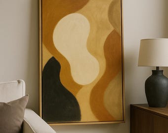 Puede incluir: Obra de arte abstracta enmarcada en madera. La pintura presenta formas orgánicas en tonos beige, marrón y negro. La obra cuelga de una pared neutra, con un sofá y una lámpara en el fondo, creando un diseño interior moderno.