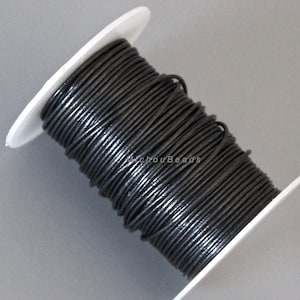 May include: A spool of black leather cord, wound around a white plastic spool.