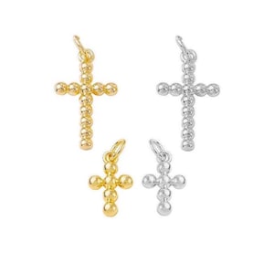 May include: Four gold and silver cross charms with a beaded design. The charms are different sizes.
