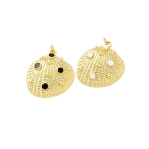 May include: Two gold-tone shell-shaped charms with a textured surface. One charm has black enamel dots and the other has white enamel dots.