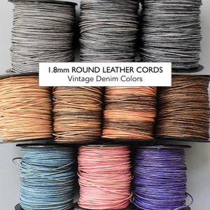 May include: Assortment of 1.8mm round leather cords in vintage denim colors. The cords are wound on spools and are available in grey, brown, peach, blue, pink, and purple.